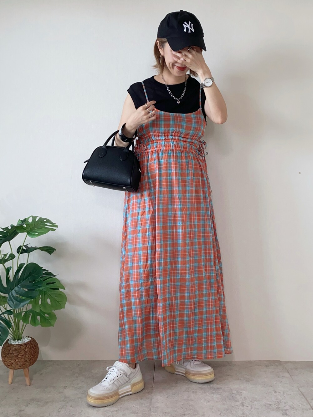 ホワイト系のスニーカー、オレンジ系のワンピース、ブラック系のボストンバッグを着用したレディースの夏コーディネートの2枚目の写真