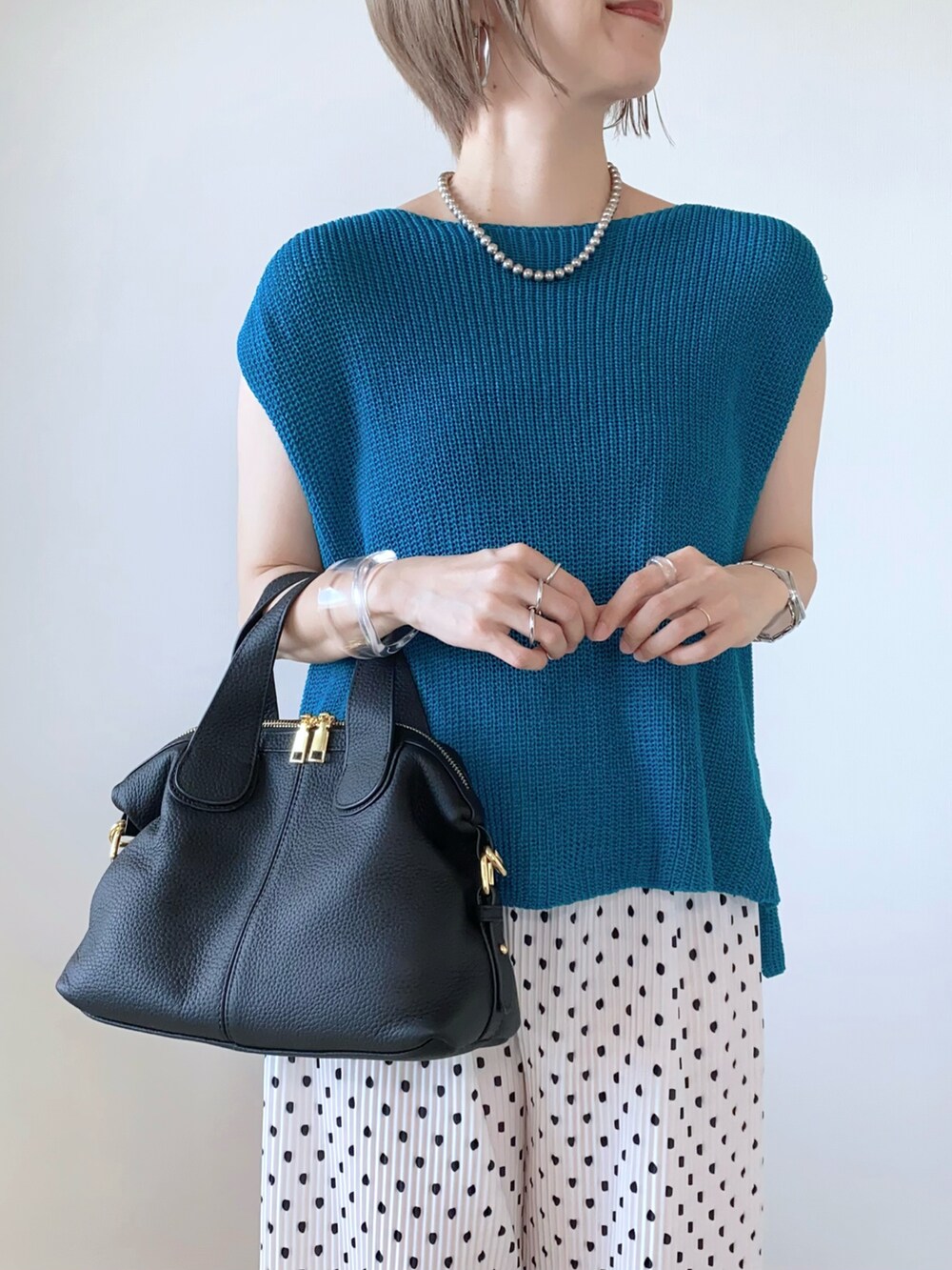 ブラック系のバッグ、ブルー系のベスト、ホワイト系のサンダルを着用したレディースの夏コーディネートの3枚目の写真