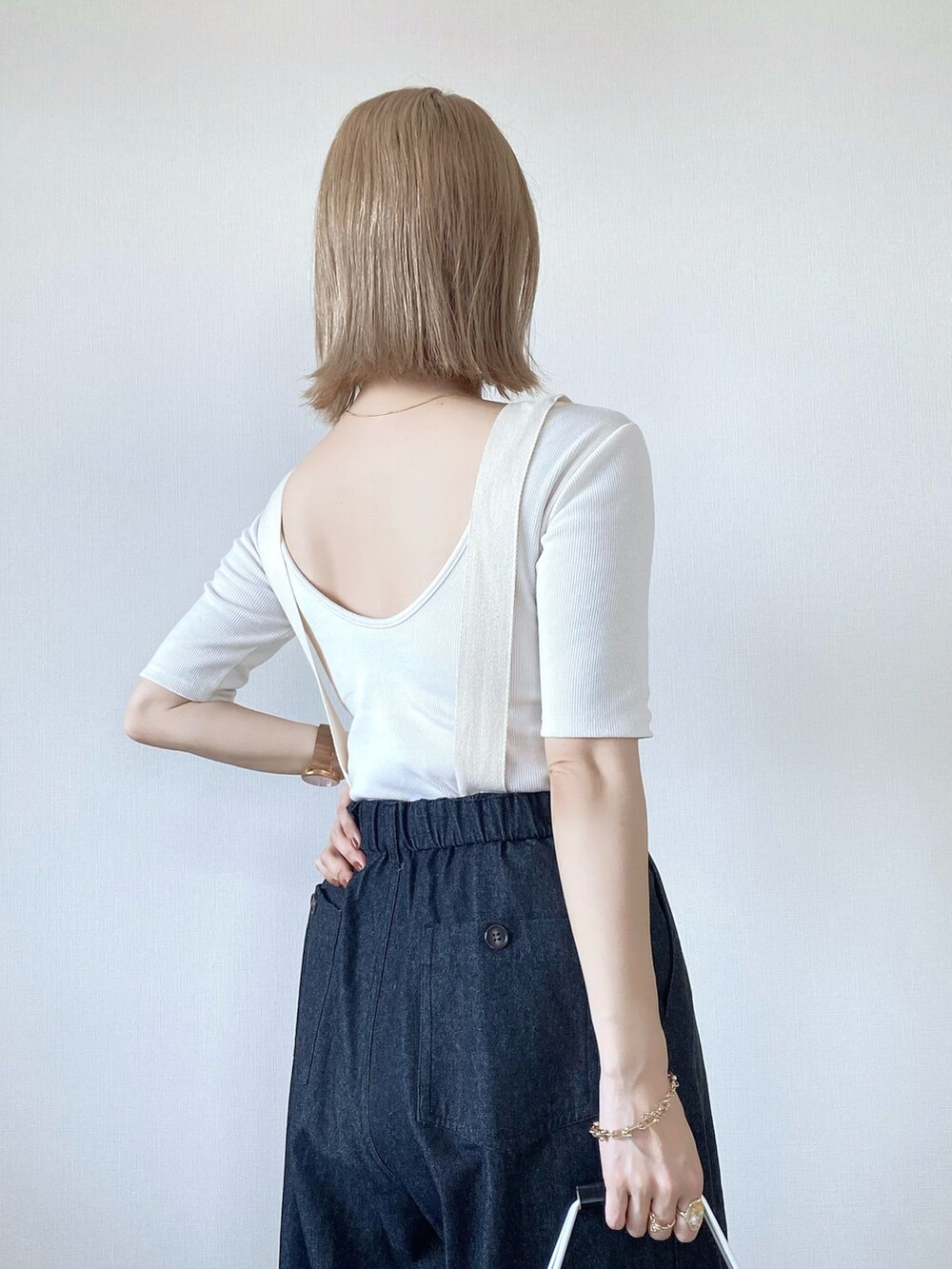 グリーン系のトートバッグ、ブラック系のデニムパンツ、ホワイト系のTシャツ/カットソーを着用したレディースの春コーディネートの3枚目の写真