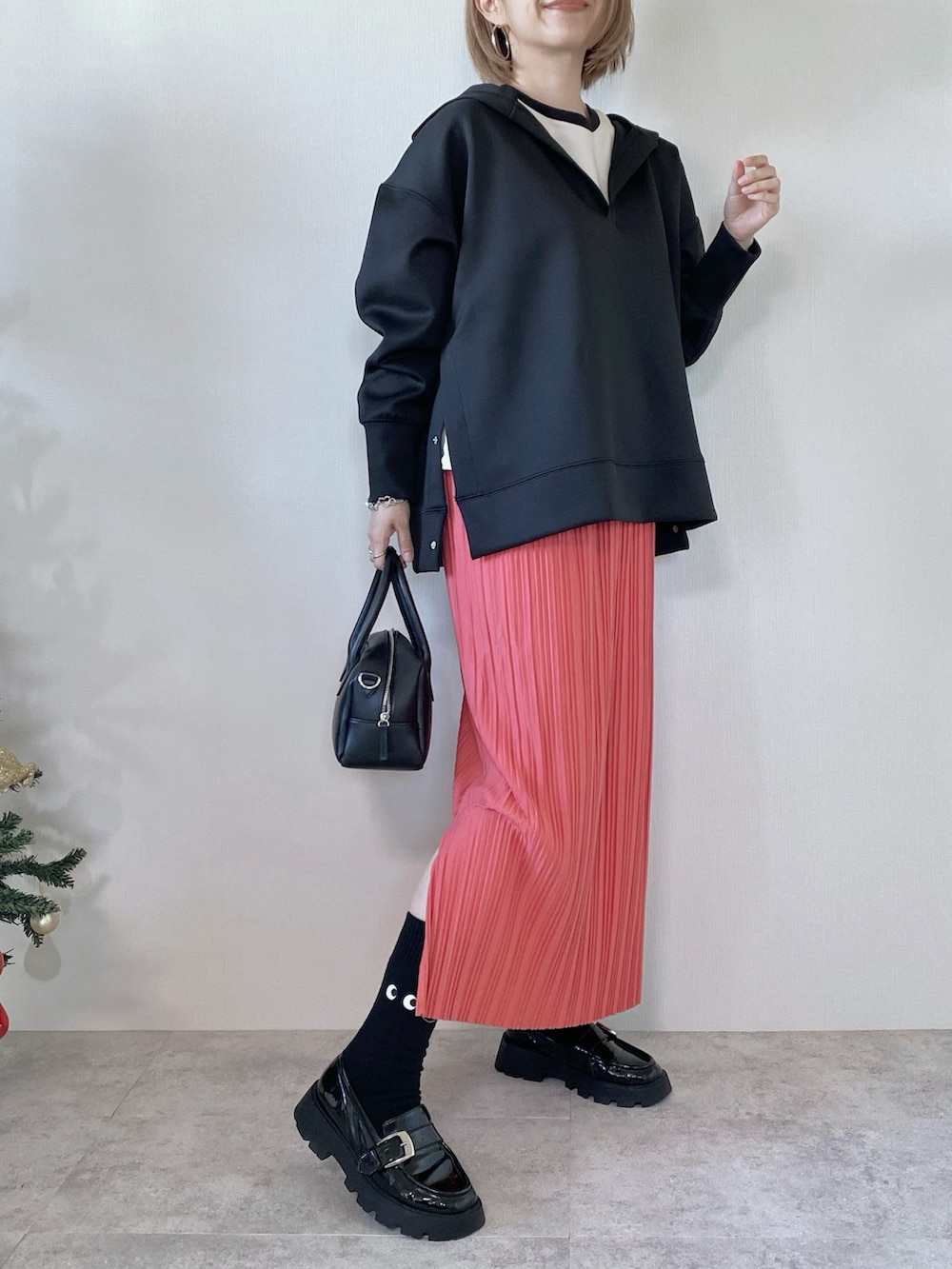 ブラック系のパーカー、ピンク系のスカート、ブラック系のローファーを着用したレディースの冬コーディネートの2枚目の写真