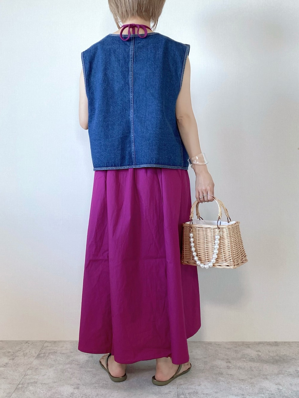 ピンク系のワンピース、ベージュ系のかごバッグ、ブルー系のベストを着用したレディースの夏コーディネートの2枚目の写真