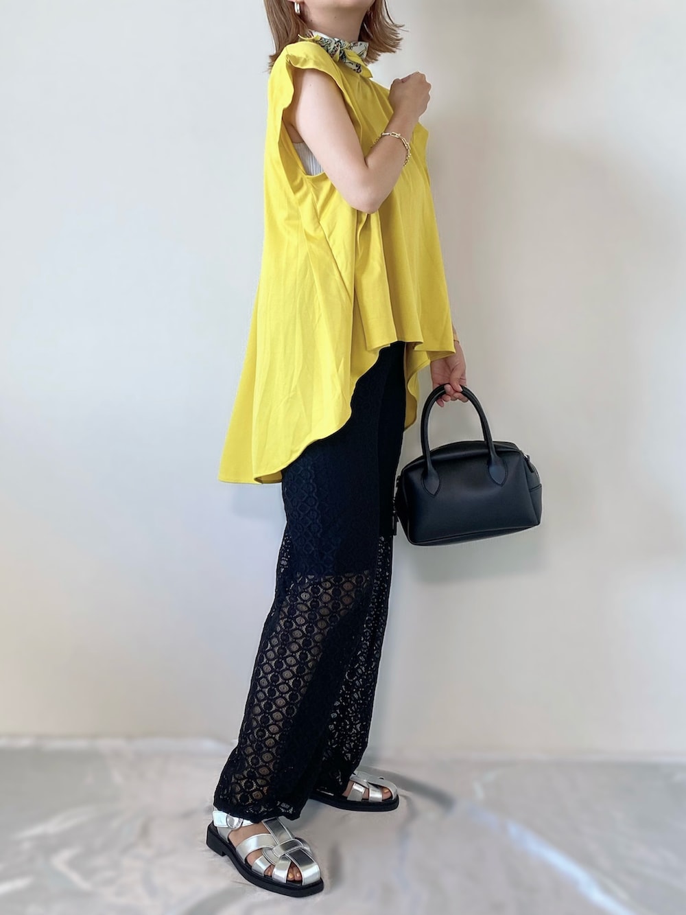 ブラック系のバッグ、イエロー系のシャツ/ブラウス、ブラック系のパンツを着用したレディースの夏コーディネートの2枚目の写真