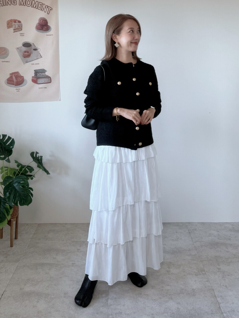 ブラック系のブーツ、ホワイト系のスカート、ブラック系のカーディガン/ボレロを着用したレディースの秋コーディネートの2枚目の写真