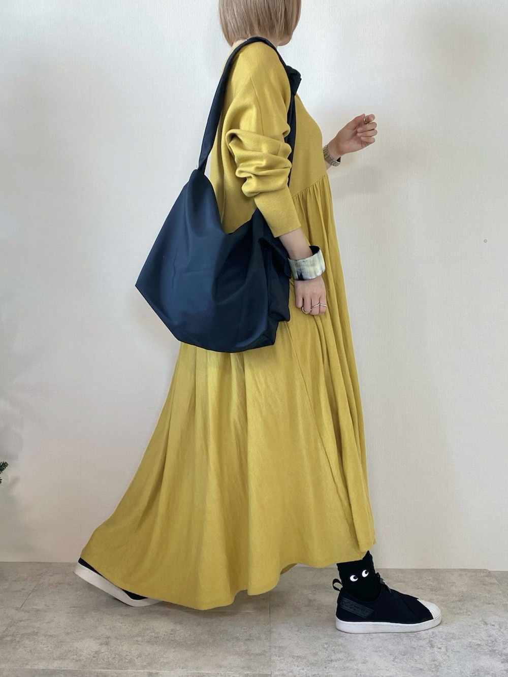 ブラック系のメッセンジャーバッグ、イエロー系のワンピース、ブラック系のスリッポンを着用したレディースの冬コーディネートの2枚目の写真