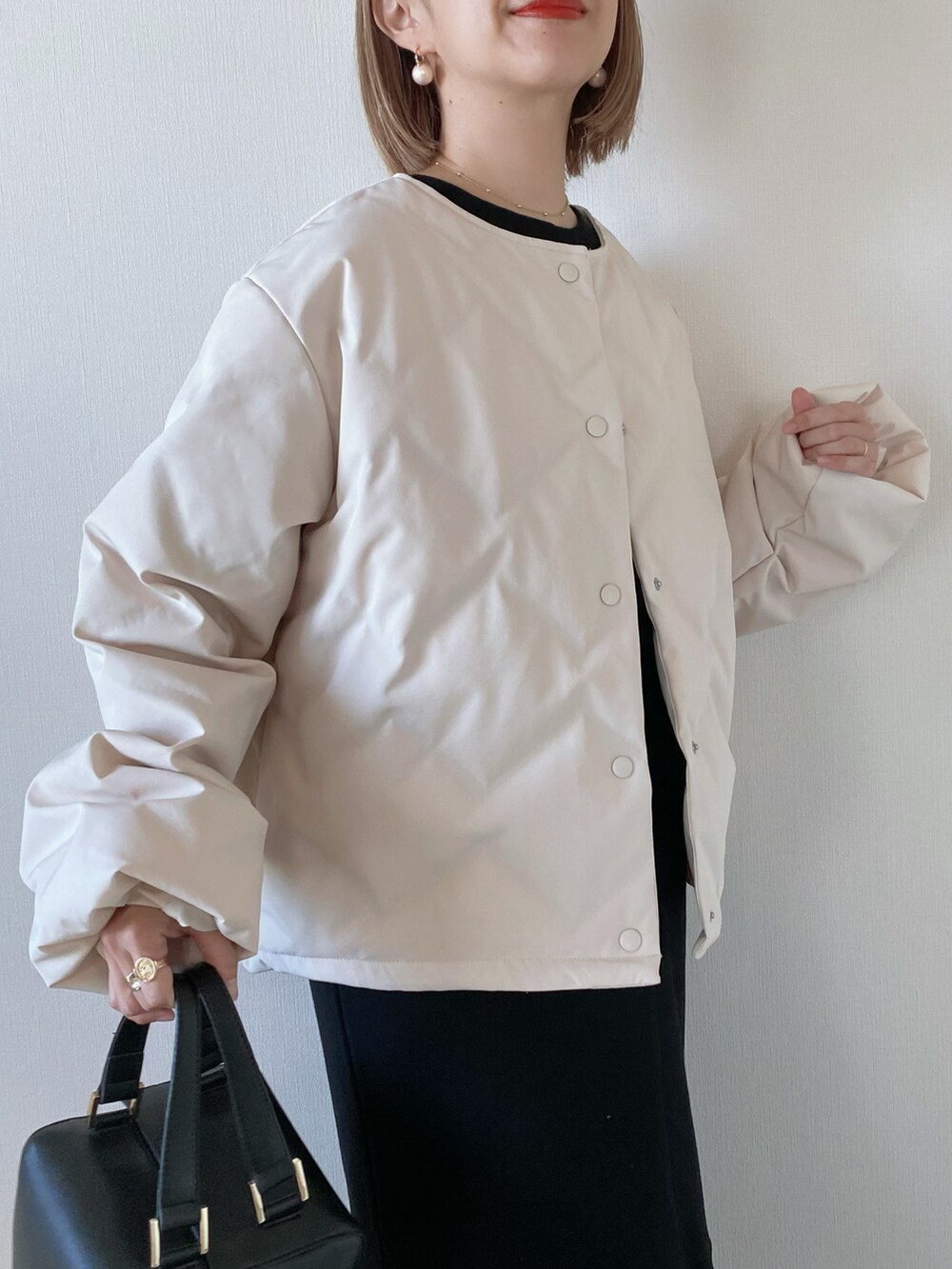 ブラック系のワンピース、ブラック系のハンドバッグ、ホワイト系のダウンジャケット/コートを着用したレディースの冬コーディネートの3枚目の写真