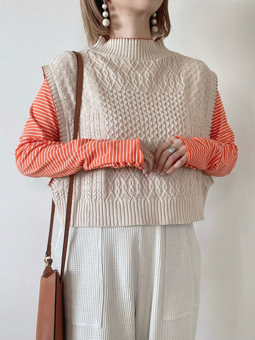 オレンジ系のTシャツ/カットソー、ベージュ系のその他パンツ、ホワイト系のベストを着用したレディースの秋コーディネートの4枚目の写真