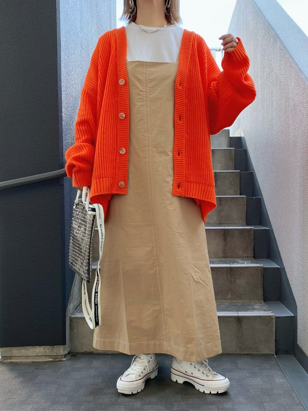 オレンジ系のカーディガン/ボレロ、ベージュ系のワンピース、ブラック系のショルダーバッグを着用したレディースの春コーディネートの3枚目の写真