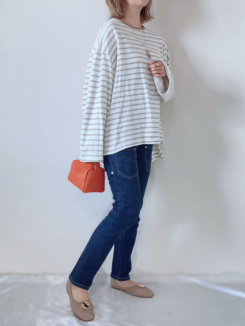 ベージュ系のバレエシューズ、オレンジ系のバッグ、グリーン系のTシャツ/カットソーを着用したレディースの春コーディネートの2枚目の写真