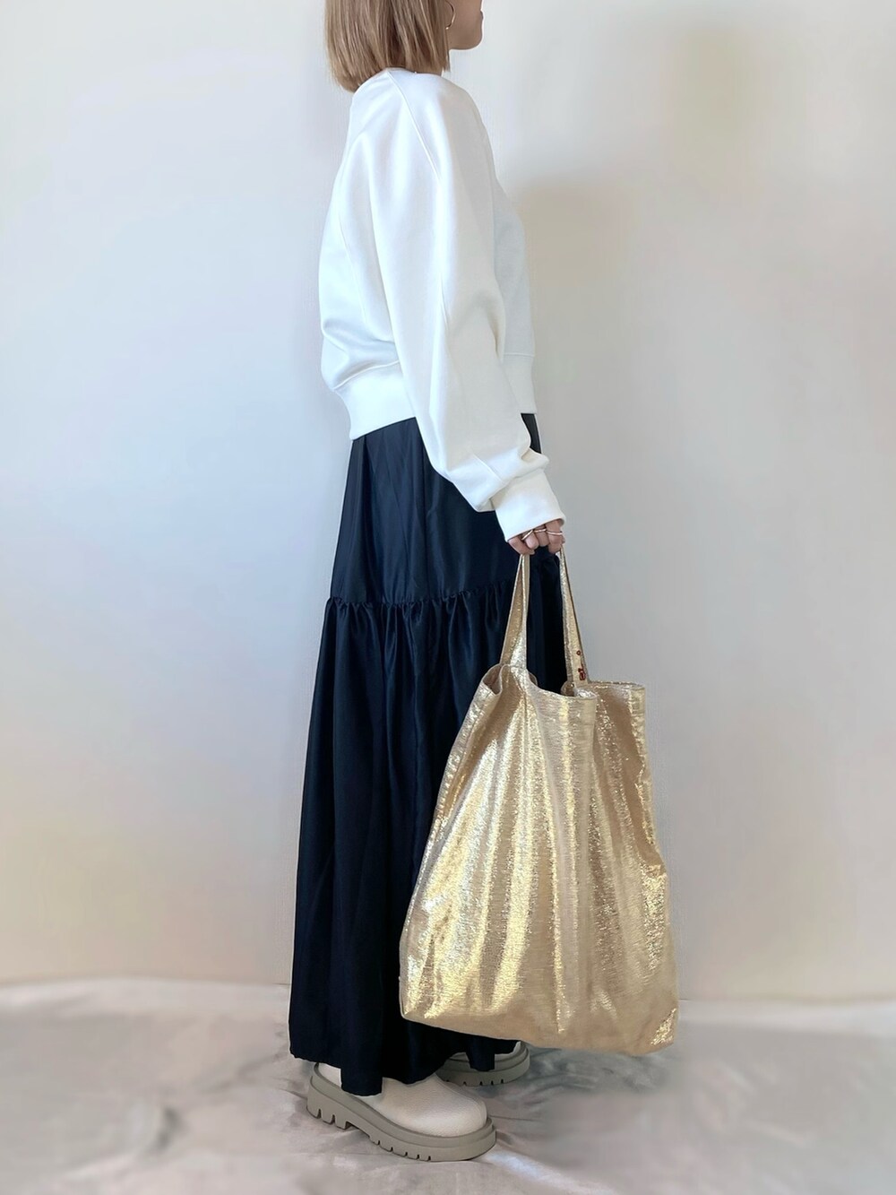 ホワイト系のスウェット、ゴールド系のトートバッグ、グレー系のワンピースを着用したレディースの冬コーディネートの2枚目の写真