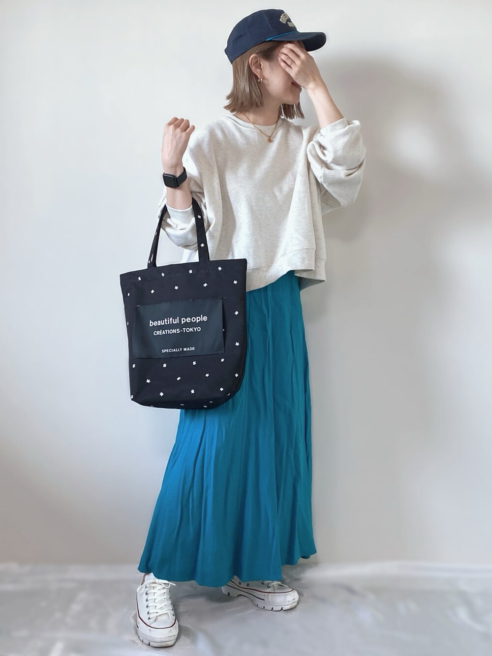 ホワイト系のトップス、ブラック系のトートバッグ、ホワイト系のスニーカーを着用したレディースの春コーディネートの2枚目の写真