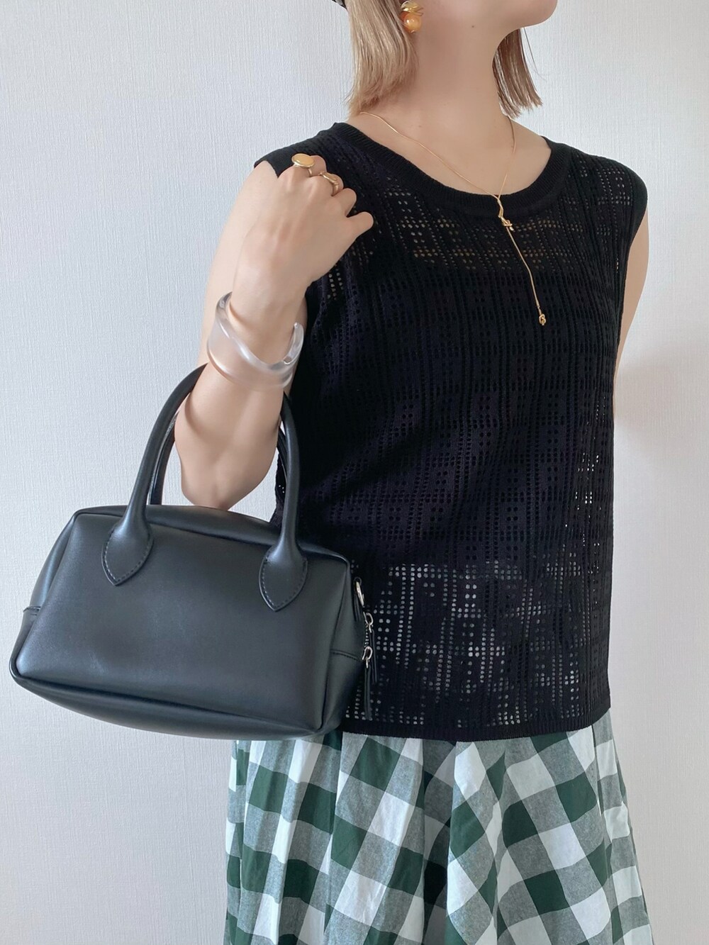 ブラック系のニット/セーター、ブラック系のバッグ、グリーン系のスカートを着用したレディースの春コーディネートの4枚目の写真