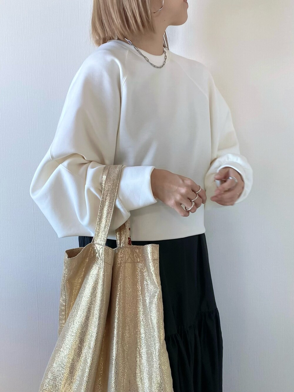 ホワイト系のスウェット、ゴールド系のトートバッグ、グレー系のワンピースを着用したレディースの冬コーディネートの3枚目の写真