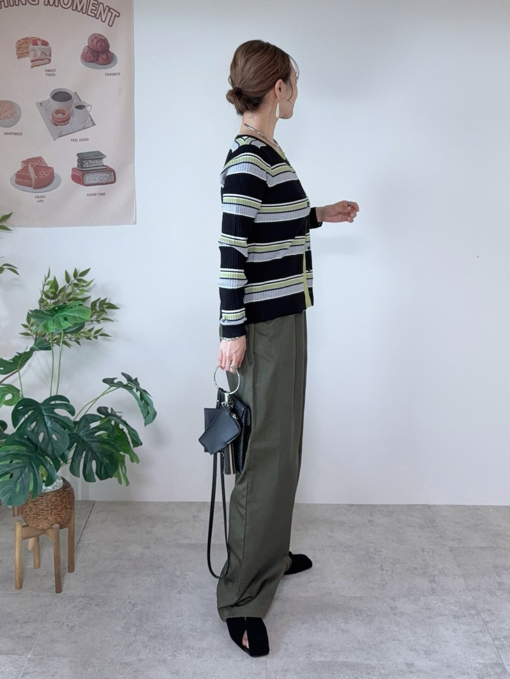 グリーン系のチノパンツ、ブラック系のパンプス、ブラック系のカーディガン/ボレロを着用したレディースの秋コーディネートの2枚目の写真