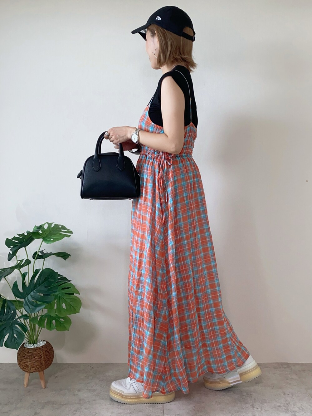 ホワイト系のスニーカー、オレンジ系のワンピース、ブラック系のボストンバッグを着用したレディースの夏コーディネートの3枚目の写真