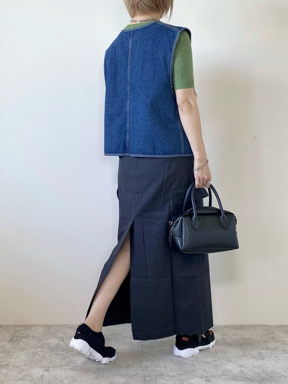 ブルー系のベスト、グリーン系のニット/セーター、グレー系のスカートを着用したレディースの秋コーディネートの2枚目の写真