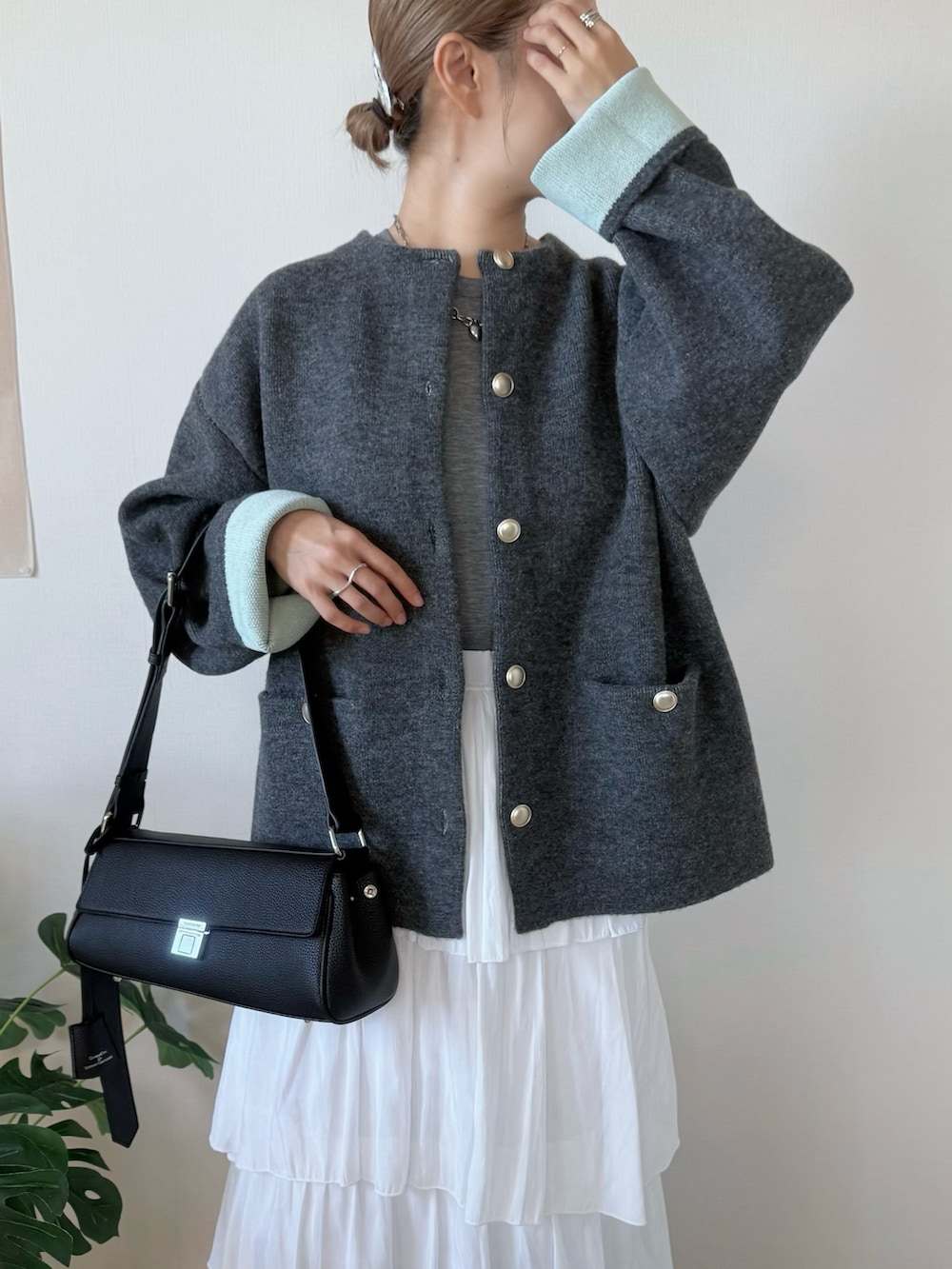 グレー系のカーディガン/ボレロ、ホワイト系のスカート、ブラック系のショルダーバッグを着用したレディースの秋コーディネートの4枚目の写真