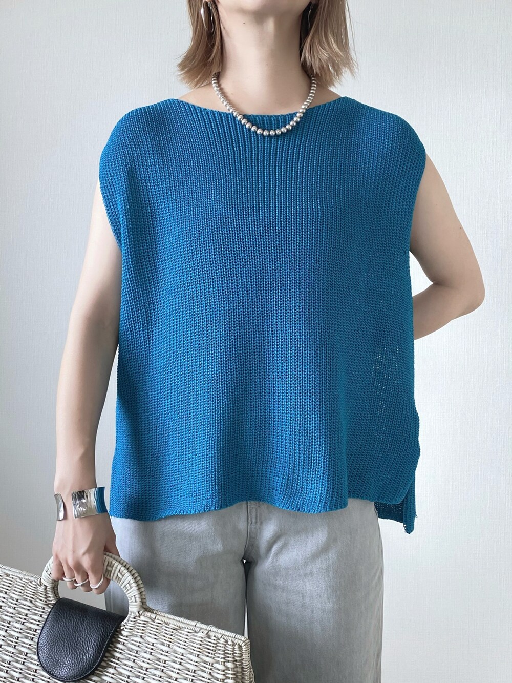 ブルー系のベスト、グレー系のデニムパンツ、ホワイト系のサンダルを着用したレディースの夏コーディネートの3枚目の写真