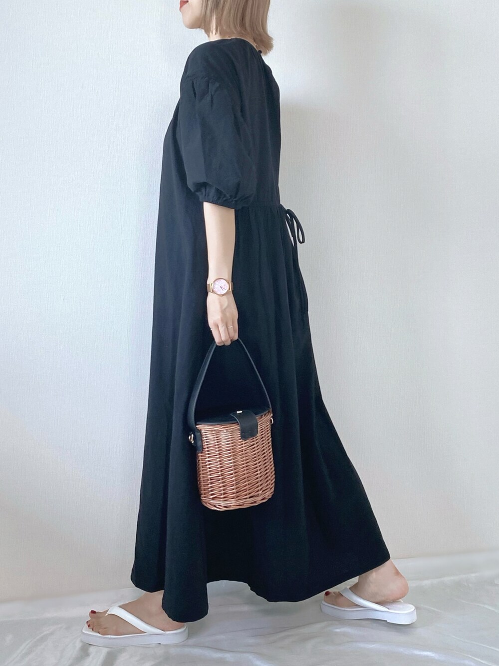 ブラック系のワンピース、ブラック系のバッグ、ホワイト系のサンダルを着用したレディースの春コーディネートの3枚目の写真