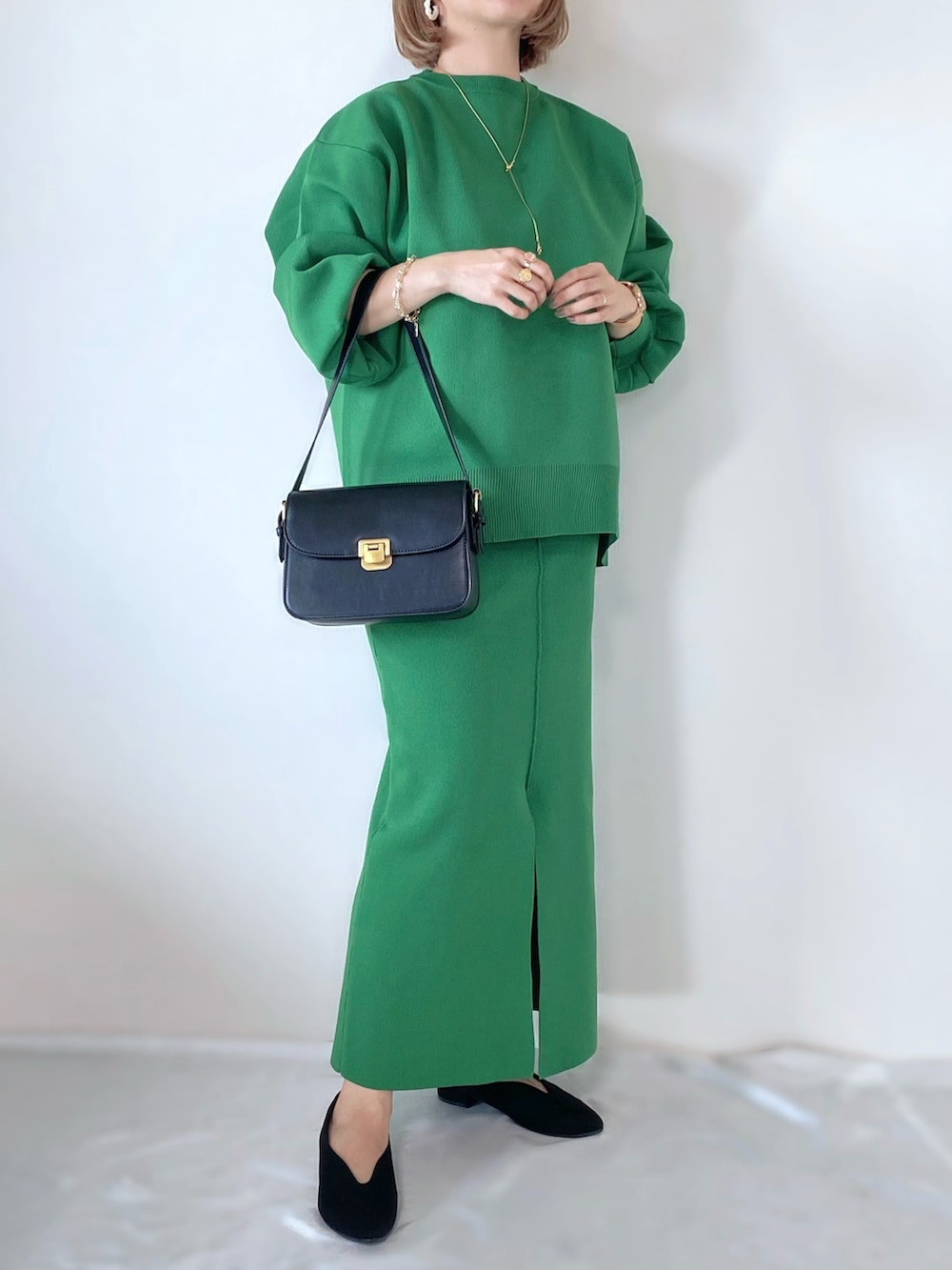 グリーン系のスカート、グリーン系のニット/セーター、ブラック系のショルダーバッグを着用したレディースの秋コーディネートの2枚目の写真
