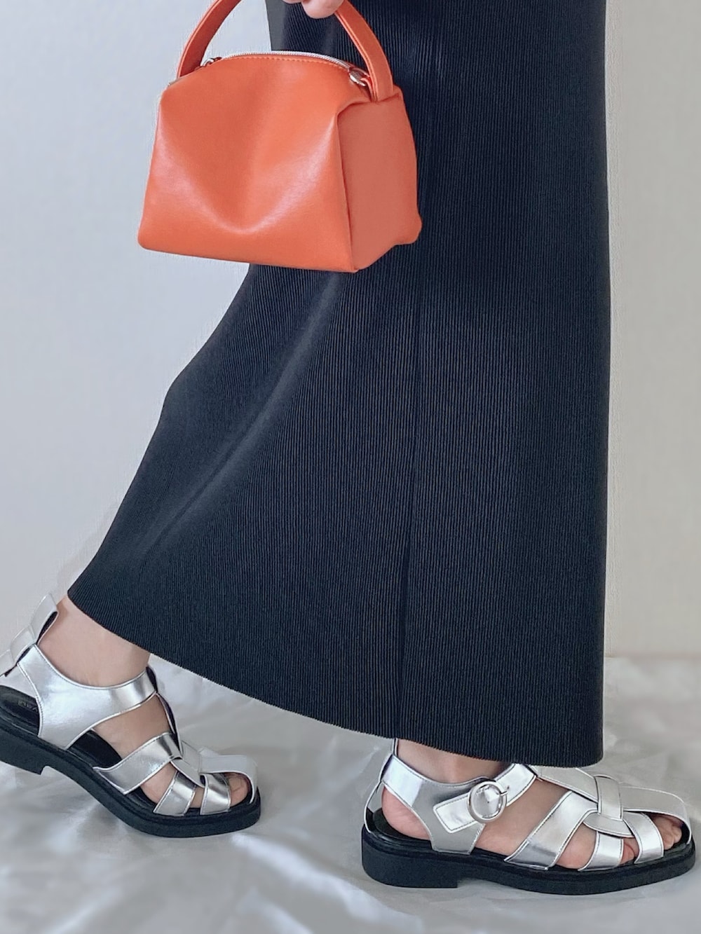 シルバー系のサンダル、オレンジ系のバッグ、ブラック系のスカートを着用したレディースの春コーディネートの3枚目の写真