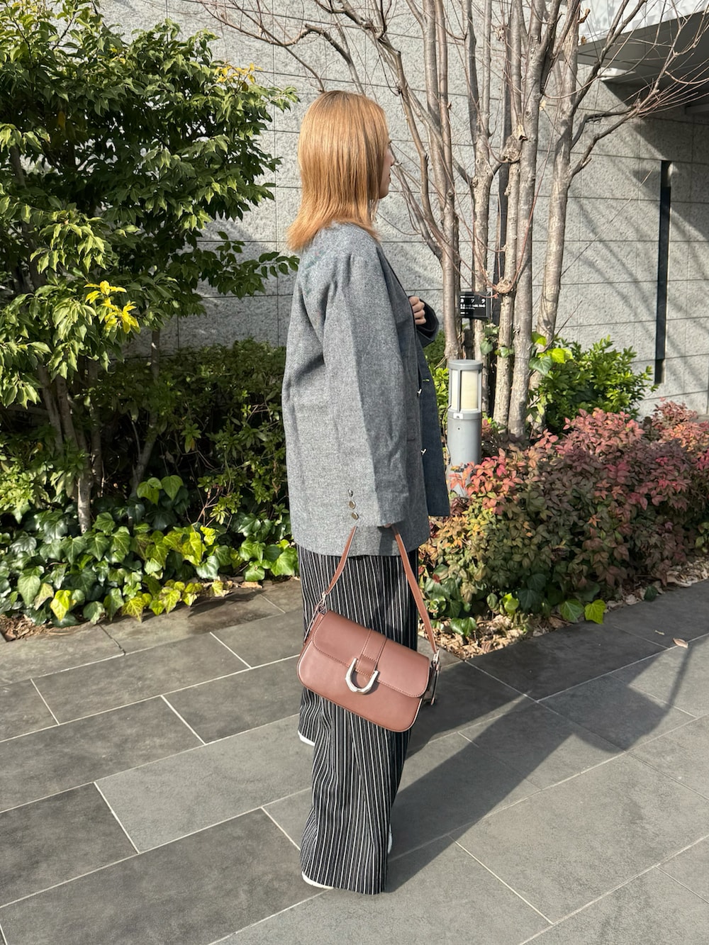 ブラック系のテーラードジャケット、ブラウン系のハンドバッグ、ブラック系のその他パンツを着用したレディースの冬コーディネートの3枚目の写真