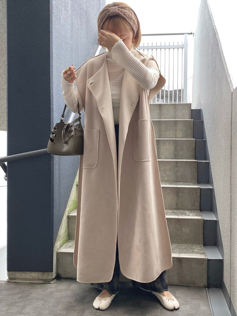 グリーン系のショルダーバッグ、ベージュ系のベスト、ホワイト系のシャツ/ブラウスを着用したレディースの秋コーディネートの2枚目の写真