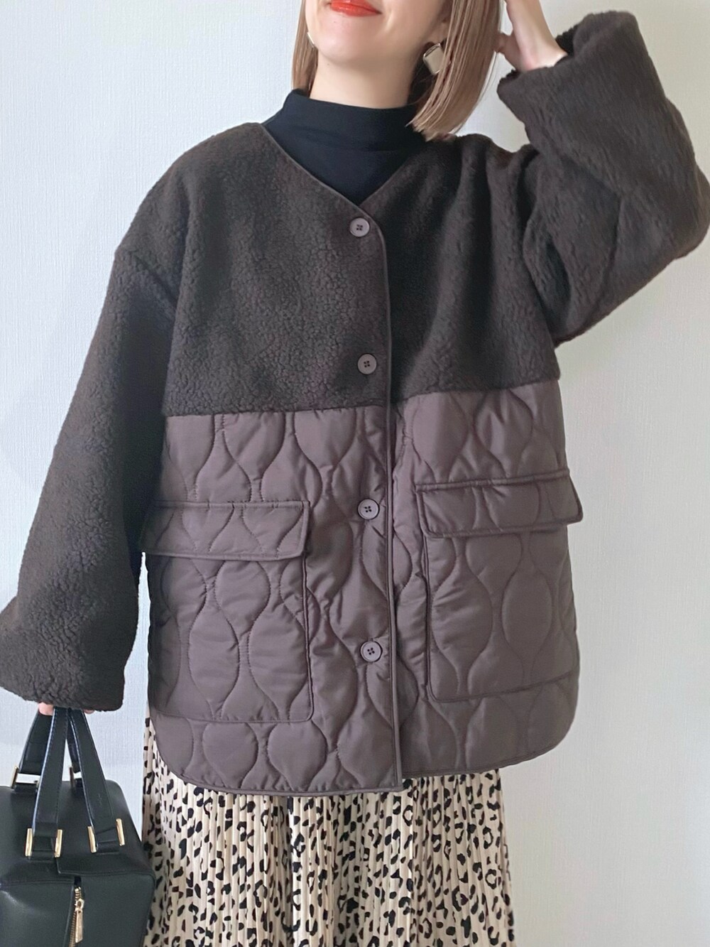 ブラック系のハンドバッグ、ブラウン系のダウンジャケット/コート、ブラウン系のブーツを着用したレディースの冬コーディネートの2枚目の写真