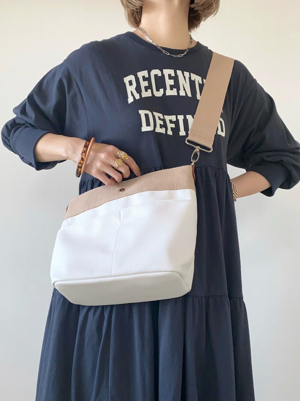 ベージュ系のショルダーバッグ、グレー系のワンピース、ホワイト系のスニーカーを着用したレディースの春コーディネートの3枚目の写真