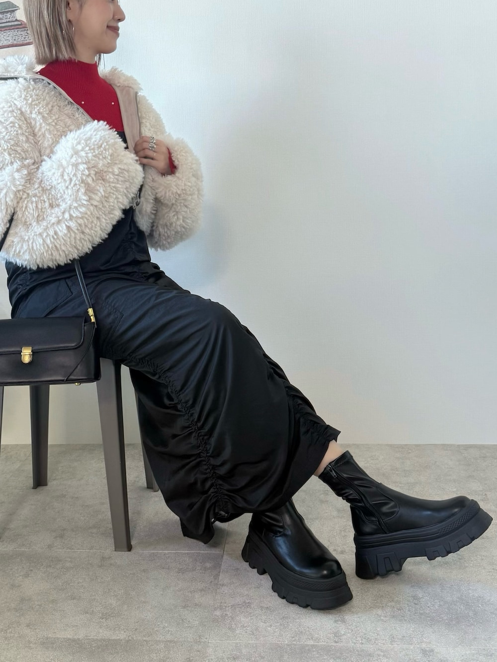 ブラック系のワンピース、ホワイト系のブルゾン、レッド系のニット/セーターを着用したレディースの冬コーディネートの2枚目の写真