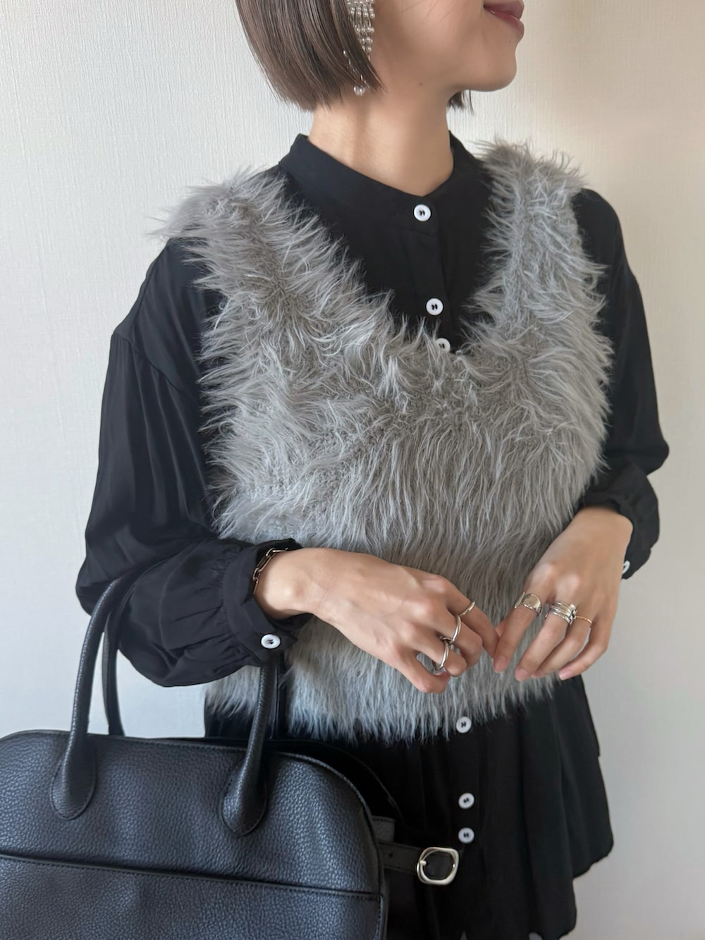 ベージュ系のベスト、ブラック系のボストンバッグ、グレー系のパンツを着用したレディースの冬コーディネートの4枚目の写真