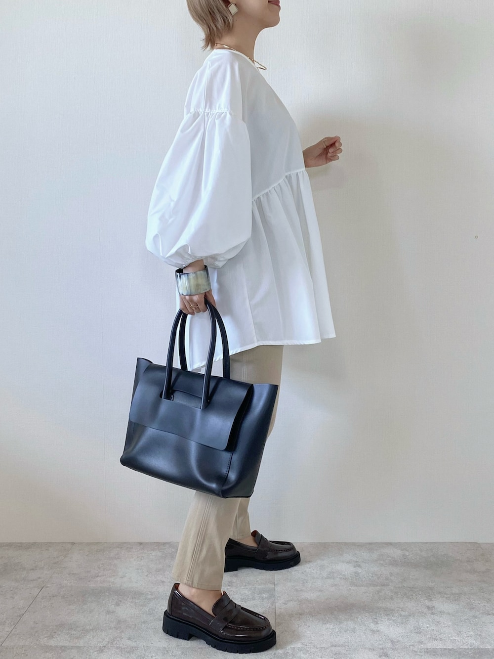 ブラック系のボストンバッグ、ホワイト系のシャツ/ブラウス、ブラウン系のローファーを着用したレディースの秋コーディネートの2枚目の写真