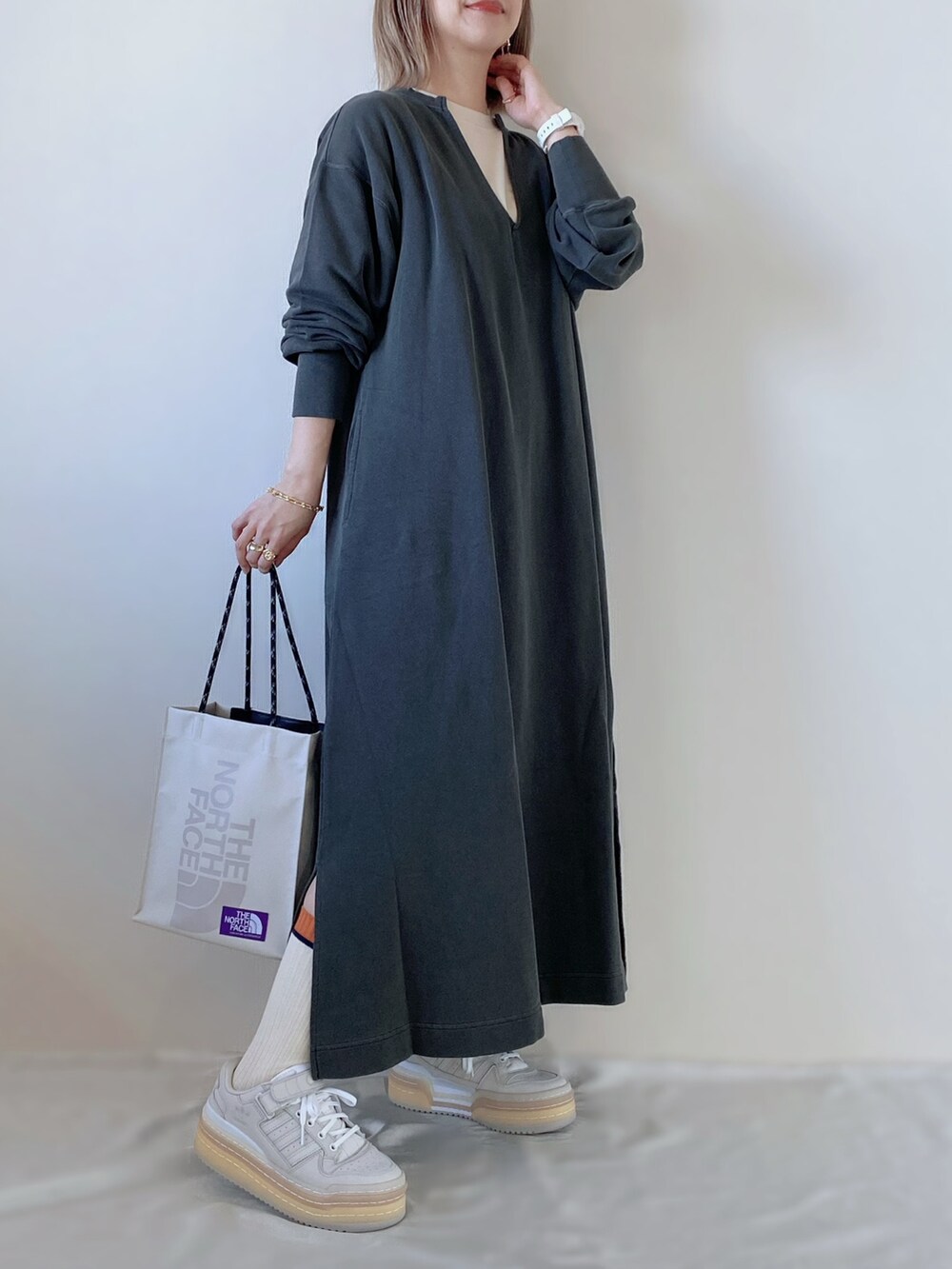 ベージュ系のトートバッグ、グレー系のワンピース、ホワイト系のスニーカーを着用したレディースの冬コーディネートの2枚目の写真