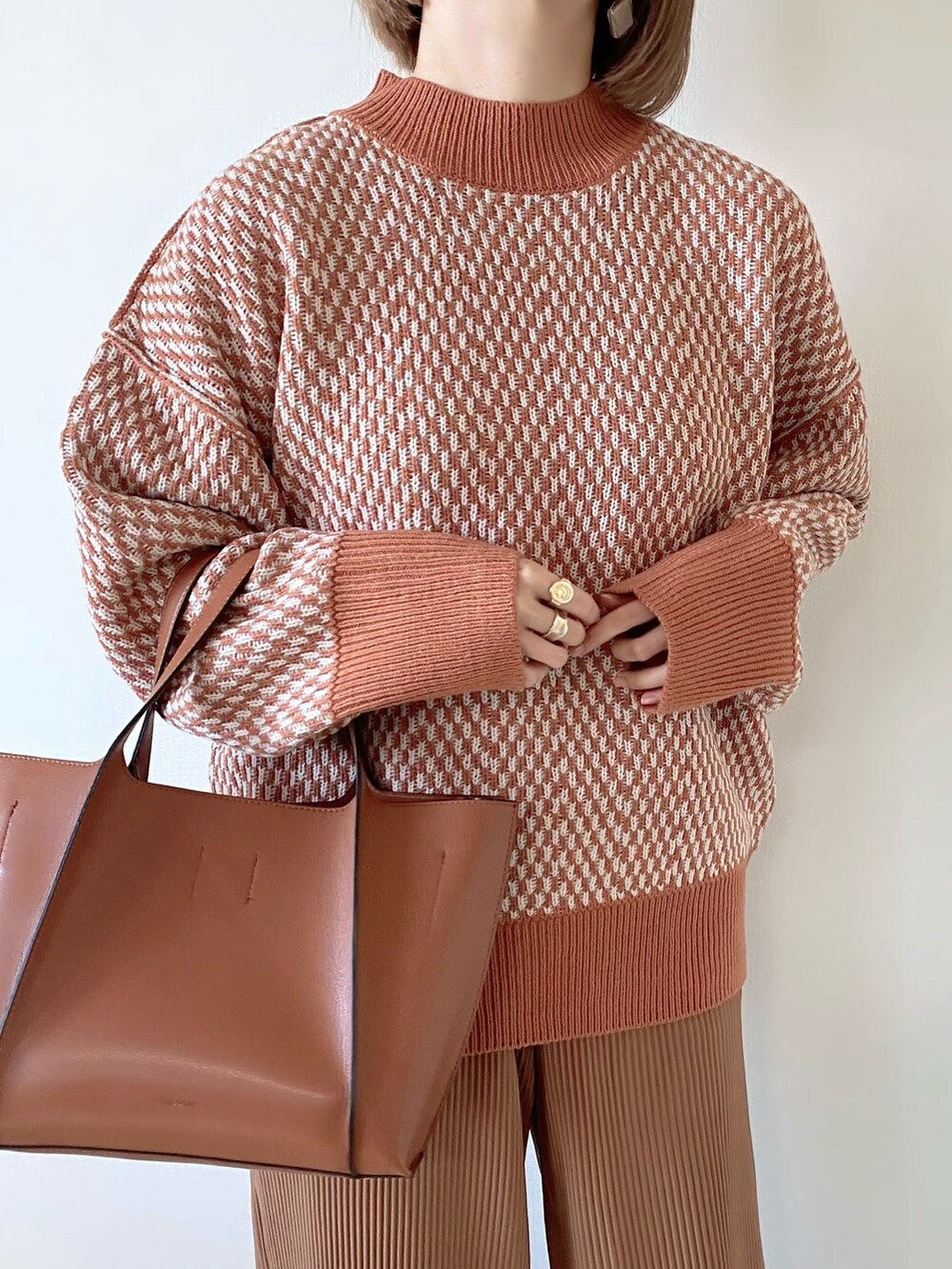 オレンジ系のニット/セーター、ブラウン系のバッグ、ホワイト系のバレエシューズを着用したレディースの秋コーディネートの4枚目の写真