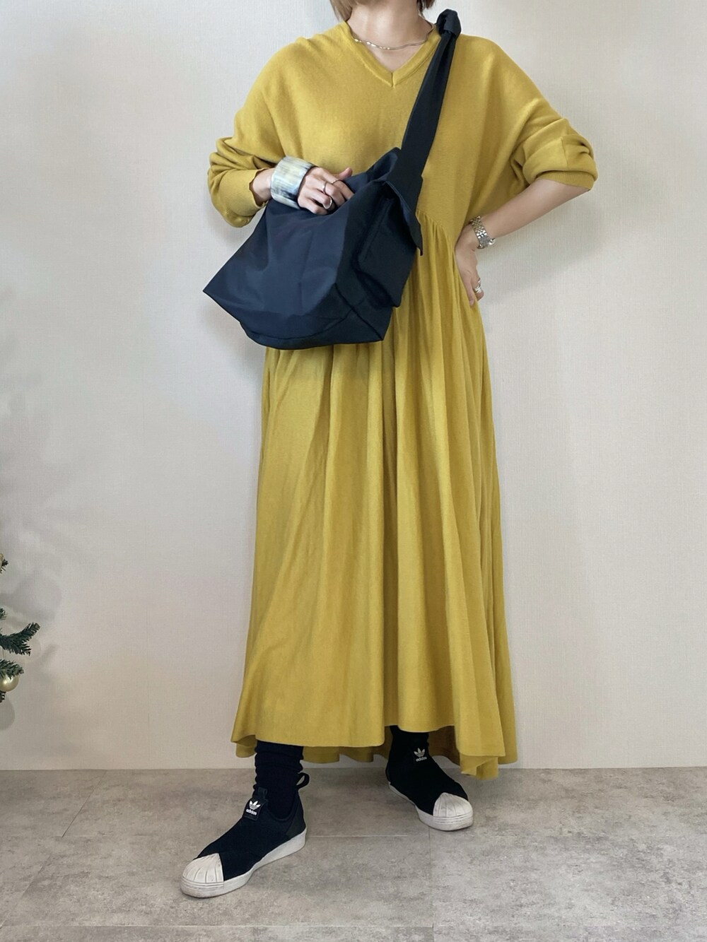 ブラック系のメッセンジャーバッグ、イエロー系のワンピース、ブラック系のスリッポンを着用したレディースの冬コーディネートの4枚目の写真