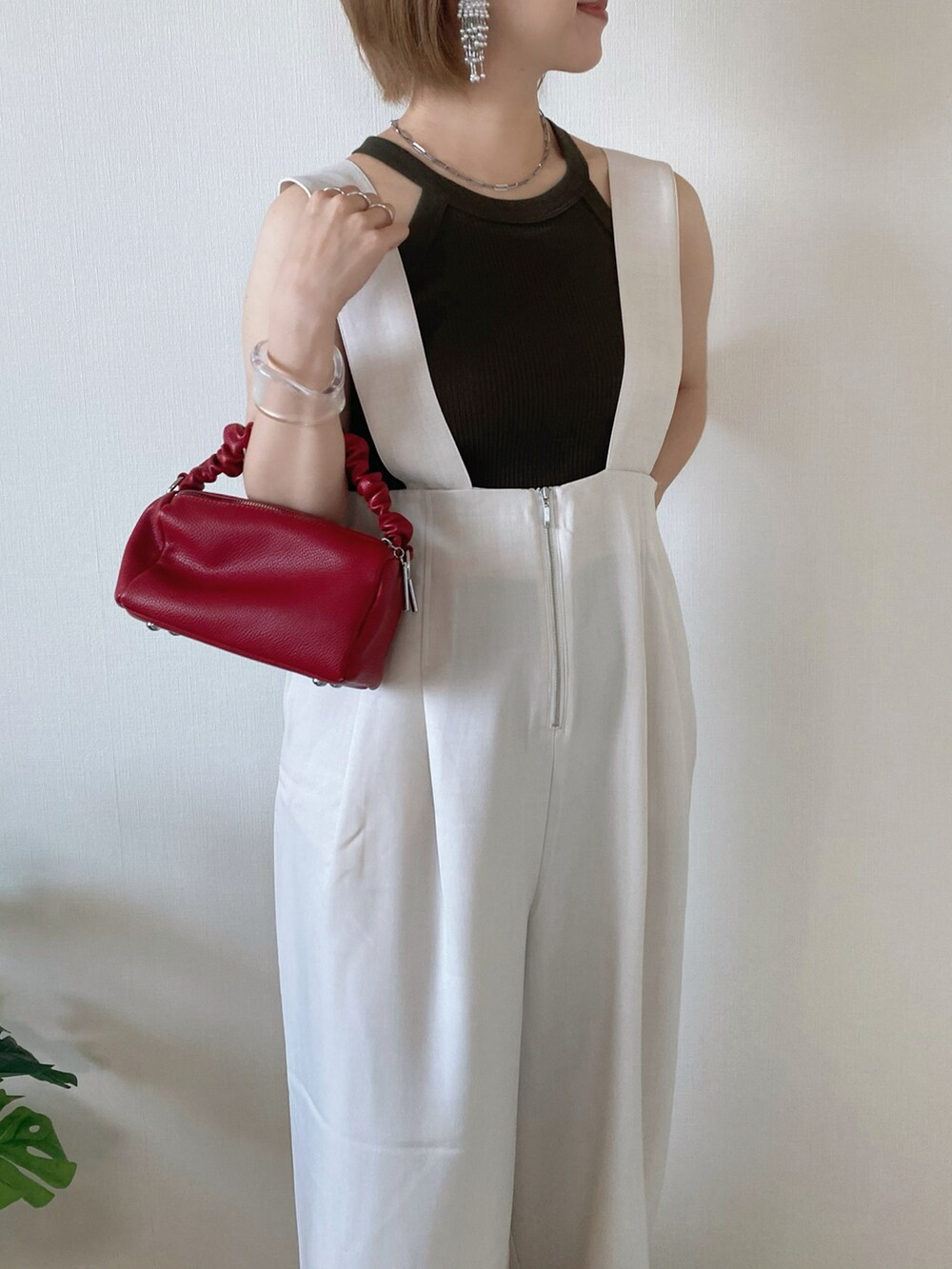 レッド系のボストンバッグ、ベージュ系のサロペット/オーバーオール、ベージュ系のサンダルを着用したレディースの夏コーディネートの3枚目の写真