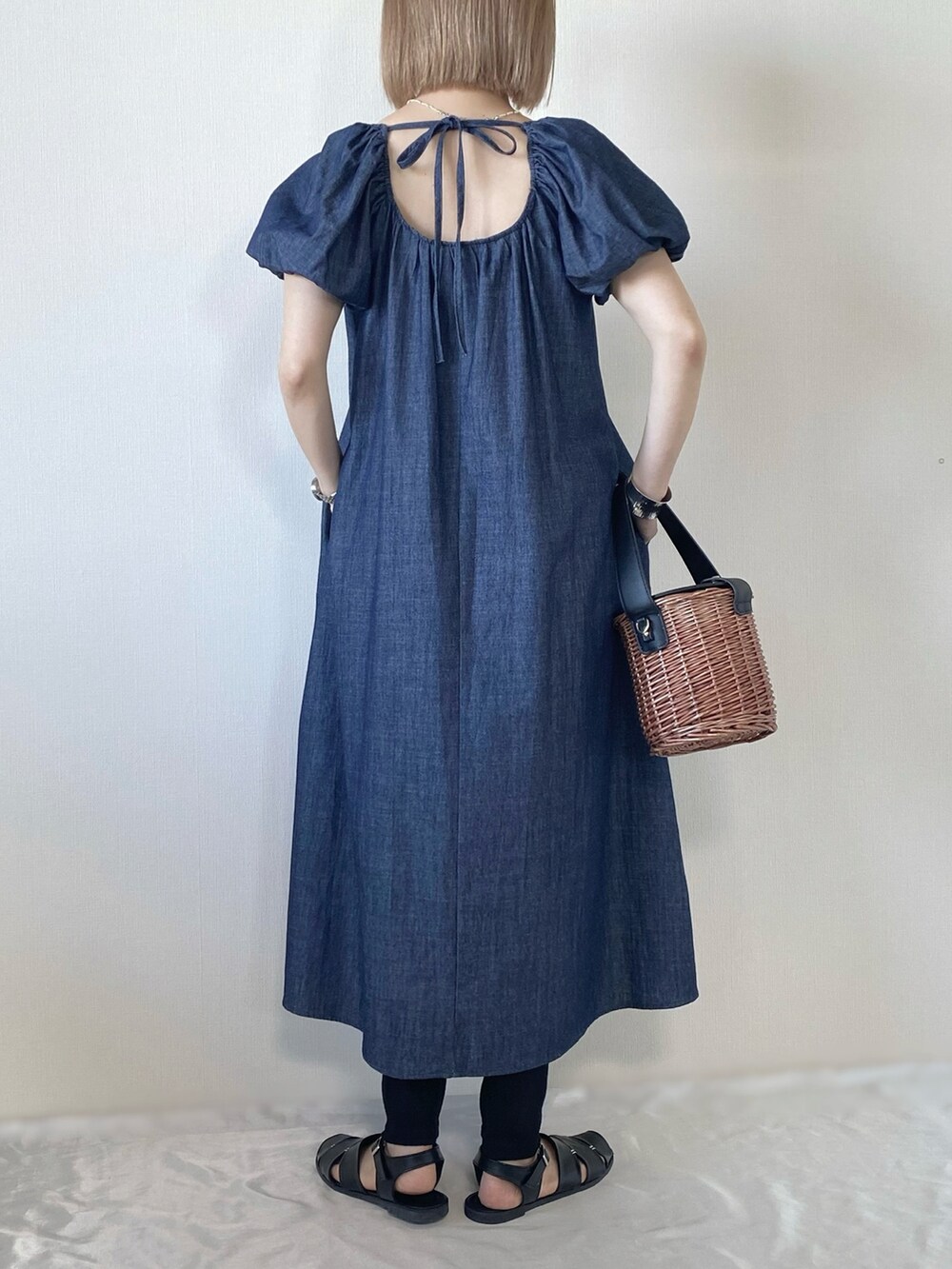 ブラック系のバッグ、ブルー系のワンピース、ブラック系のサンダルを着用したレディースの春コーディネートの3枚目の写真