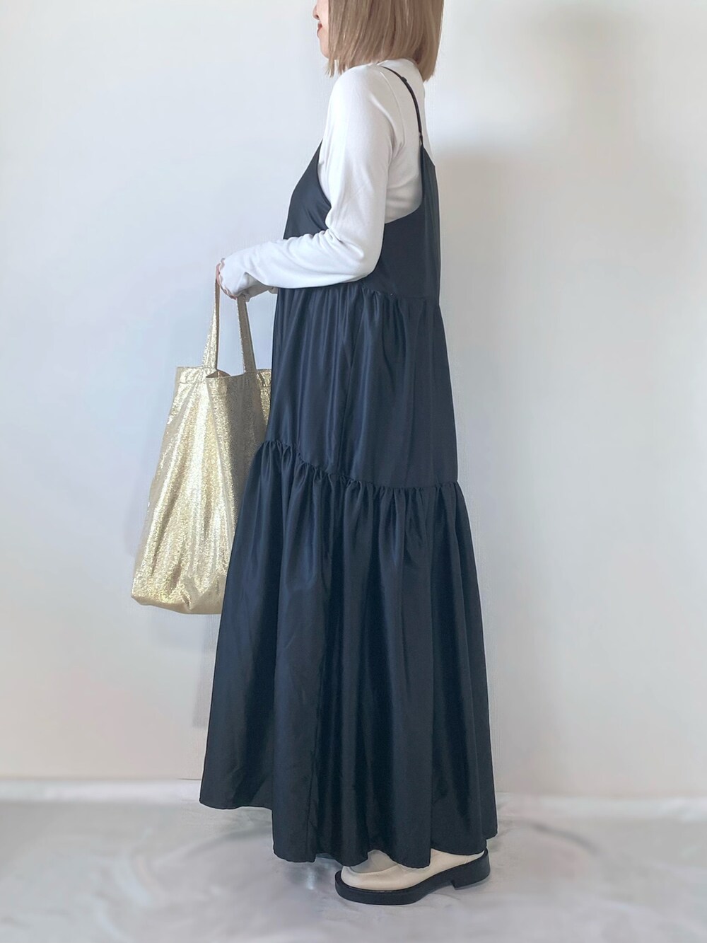 ゴールド系のトートバッグ、グレー系のワンピース、ホワイト系のトップスを着用したレディースの春コーディネートの3枚目の写真