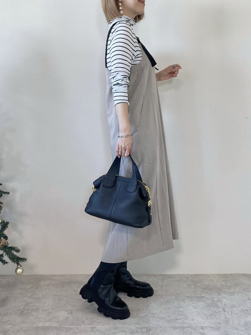 グレー系のジャンパースカート、ブラック系のバッグ、ホワイト系のTシャツ/カットソーを着用したレディースの冬コーディネートの3枚目の写真