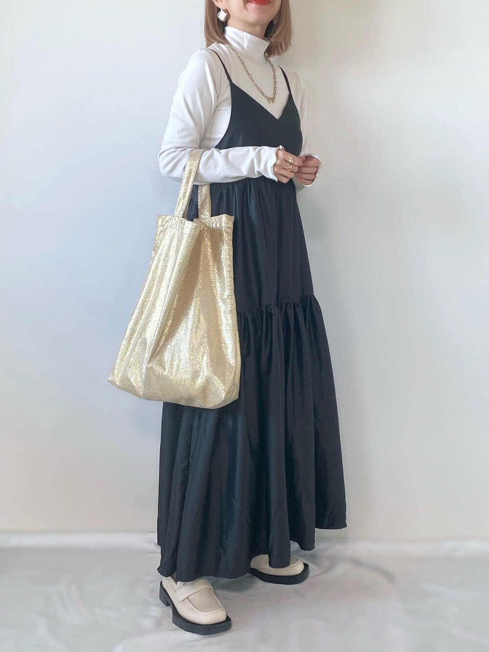 ゴールド系のトートバッグ、グレー系のワンピース、ホワイト系のトップスを着用したレディースの春コーディネートの2枚目の写真