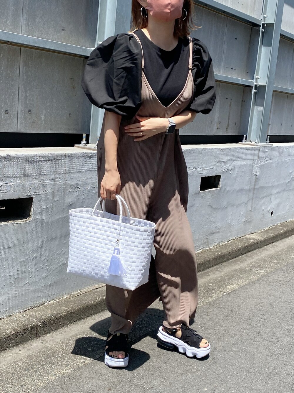 ブラック系のトップス、ホワイト系のかごバッグ、ブラック系のサンダルを着用したレディースの夏コーディネートの2枚目の写真