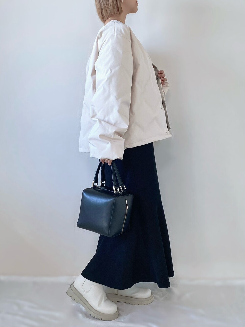 ブラック系のワンピース、ブラック系のハンドバッグ、ホワイト系のダウンジャケット/コートを着用したレディースの冬コーディネートの2枚目の写真