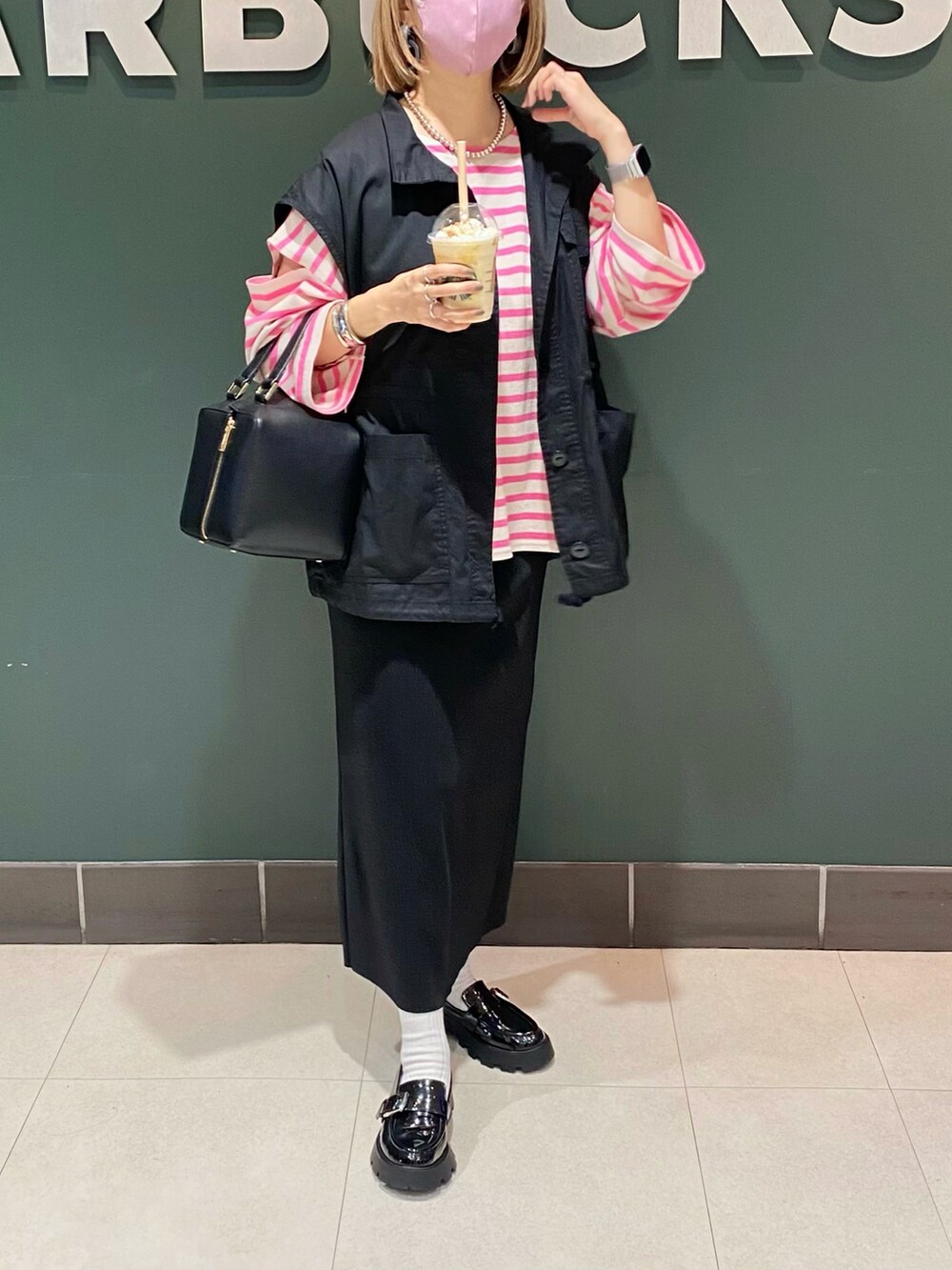 ブラック系のベスト、ピンク系のTシャツ/カットソー、ブラック系のハンドバッグを着用したレディースの秋コーディネートの4枚目の写真