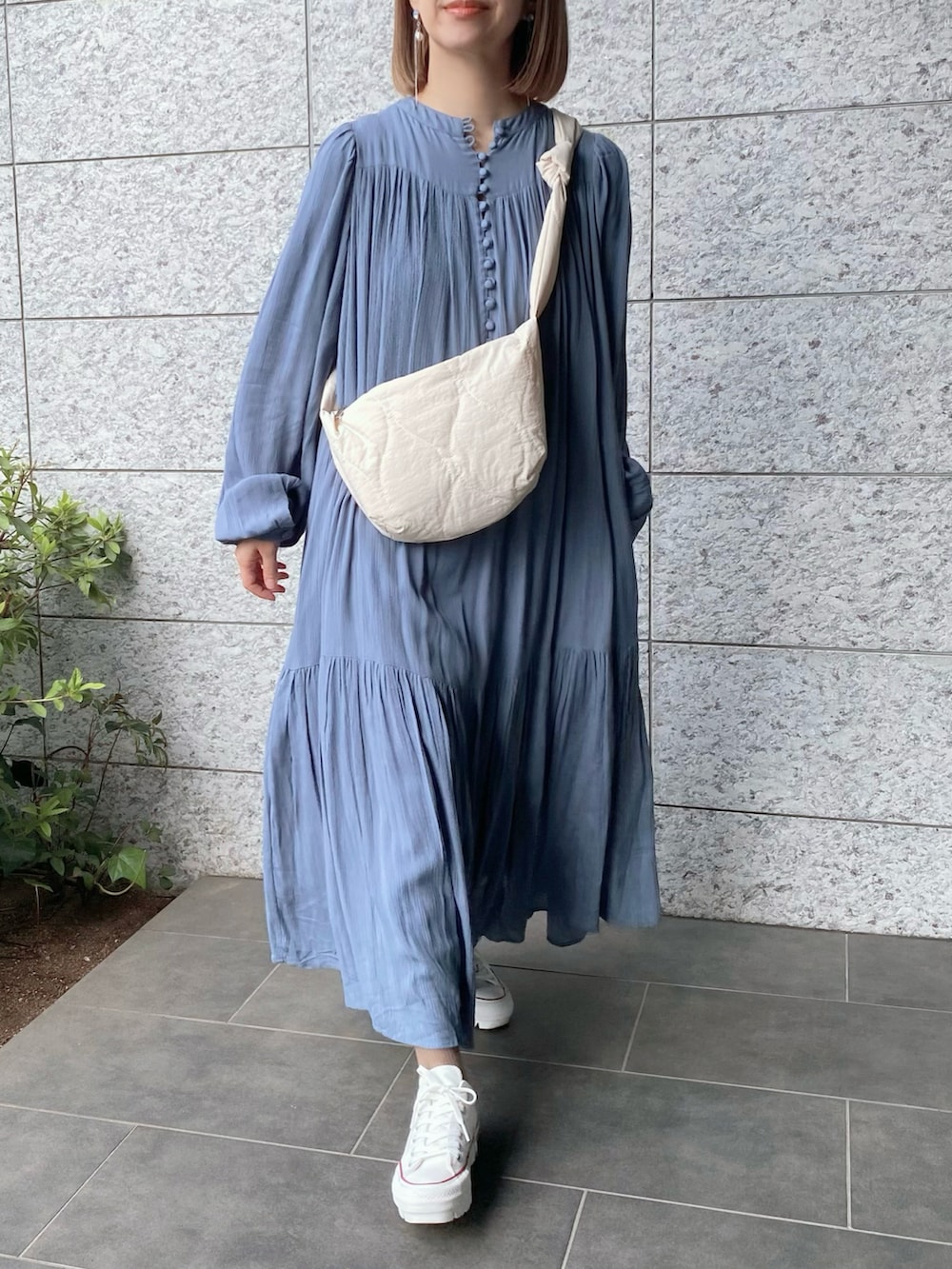 ホワイト系のショルダーバッグ、ブルー系のワンピース、ホワイト系のスニーカーを着用したレディースの春コーディネートの2枚目の写真
