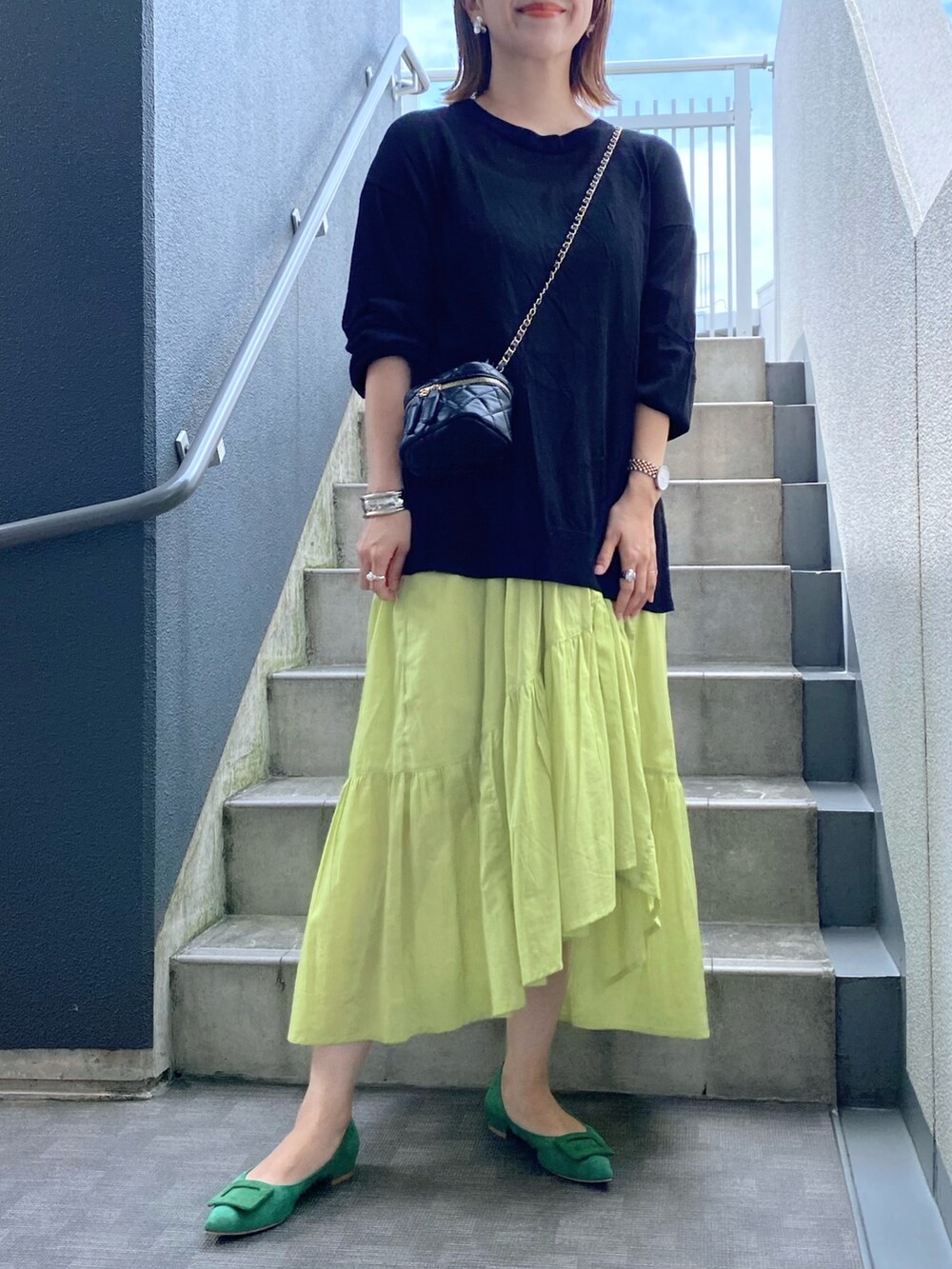 グリーン系のパンプス、イエロー系のワンピース、ブラック系のショルダーバッグを着用したレディースの夏コーディネートの2枚目の写真