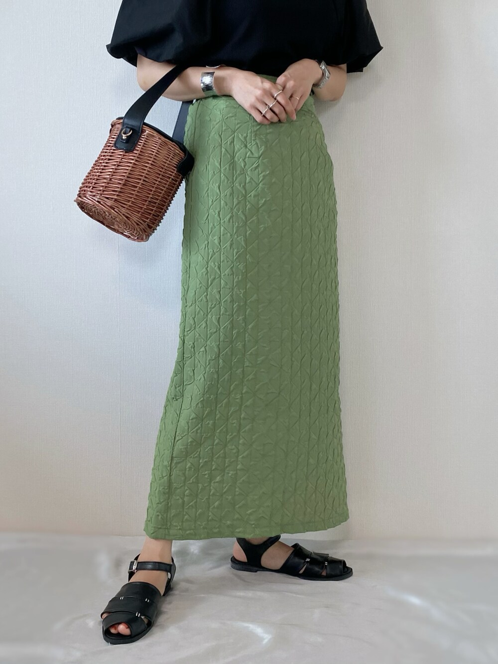 グリーン系のスカート、ブラック系のトップス、ブラック系のバッグを着用したレディースの夏コーディネートの5枚目の写真