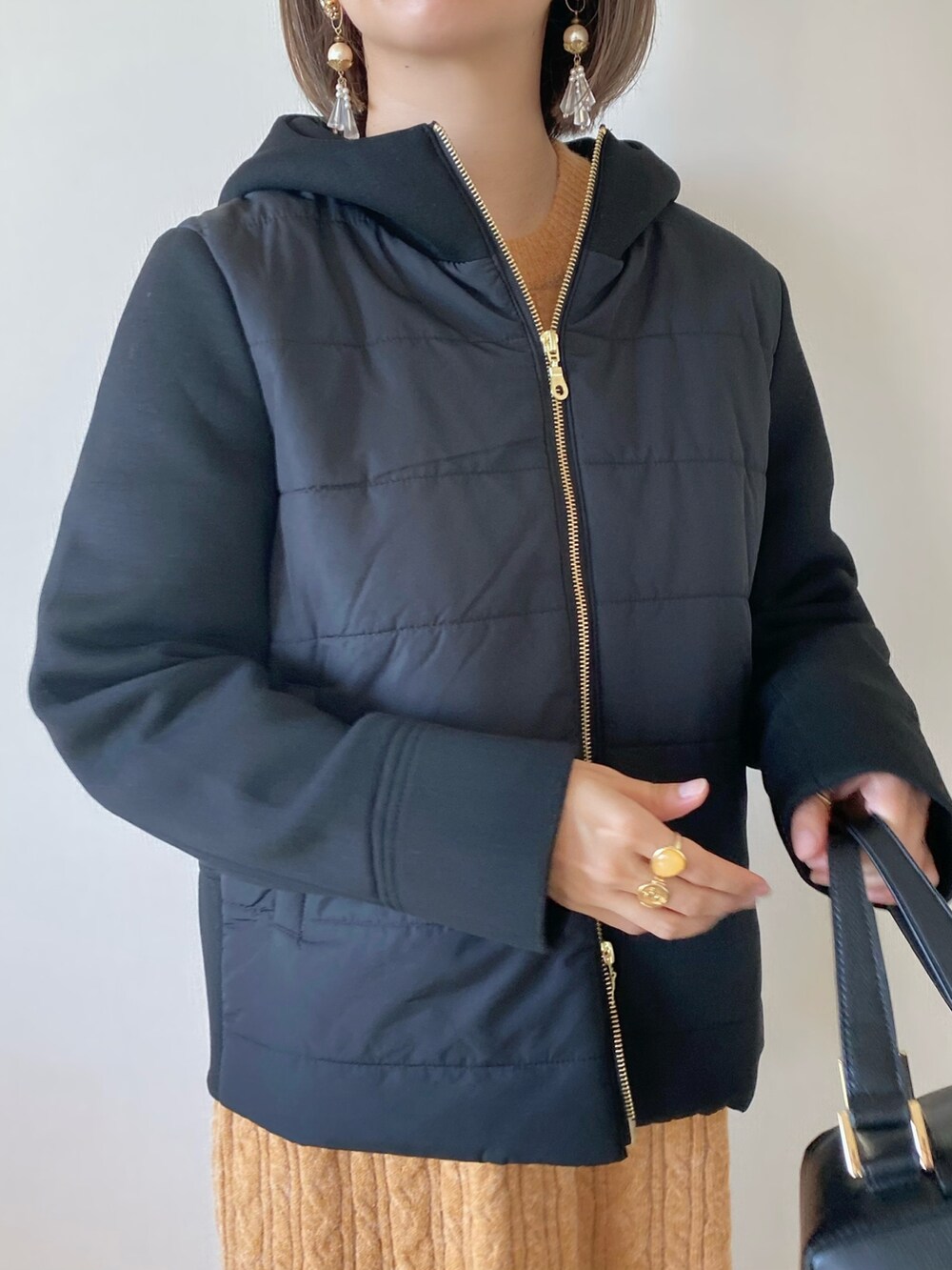 ブラック系のブルゾン、オレンジ系のワンピース、ブラック系のハンドバッグを着用したレディースの秋コーディネートの3枚目の写真