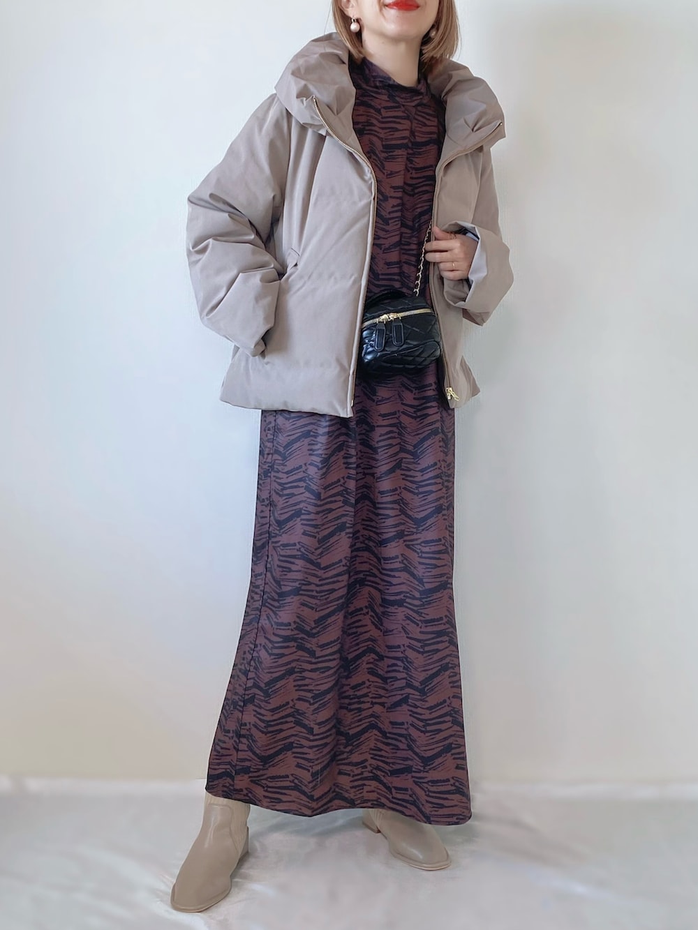 ブラウン系のダウンジャケット/コート、ブラウン系のワンピース、ベージュ系のブーツを着用したレディースの冬コーディネートの2枚目の写真