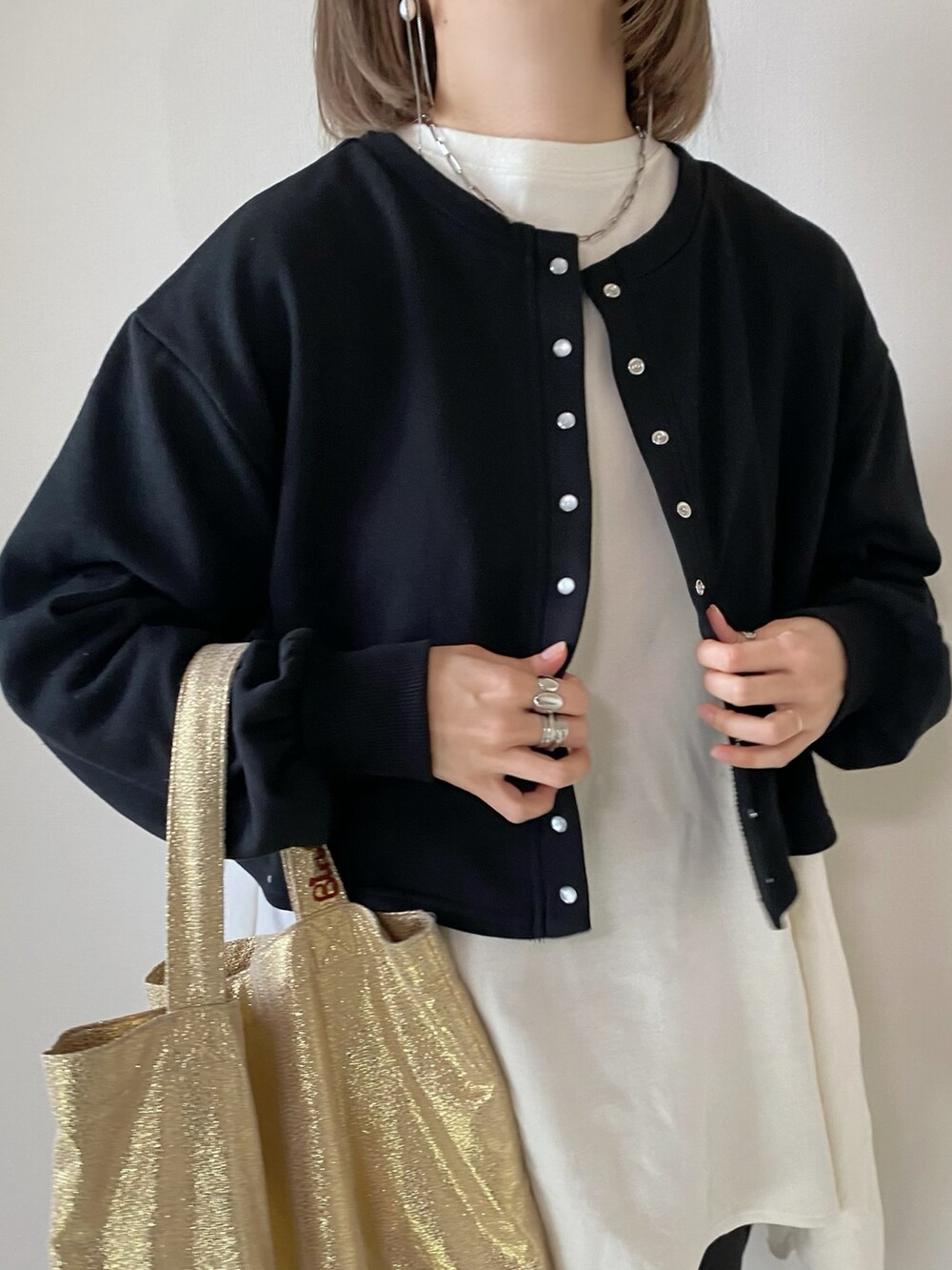 ブラック系のカーディガン/ボレロ、ホワイト系のTシャツ/カットソー、ブラック系のスラックスを着用したレディースの冬コーディネートの4枚目の写真