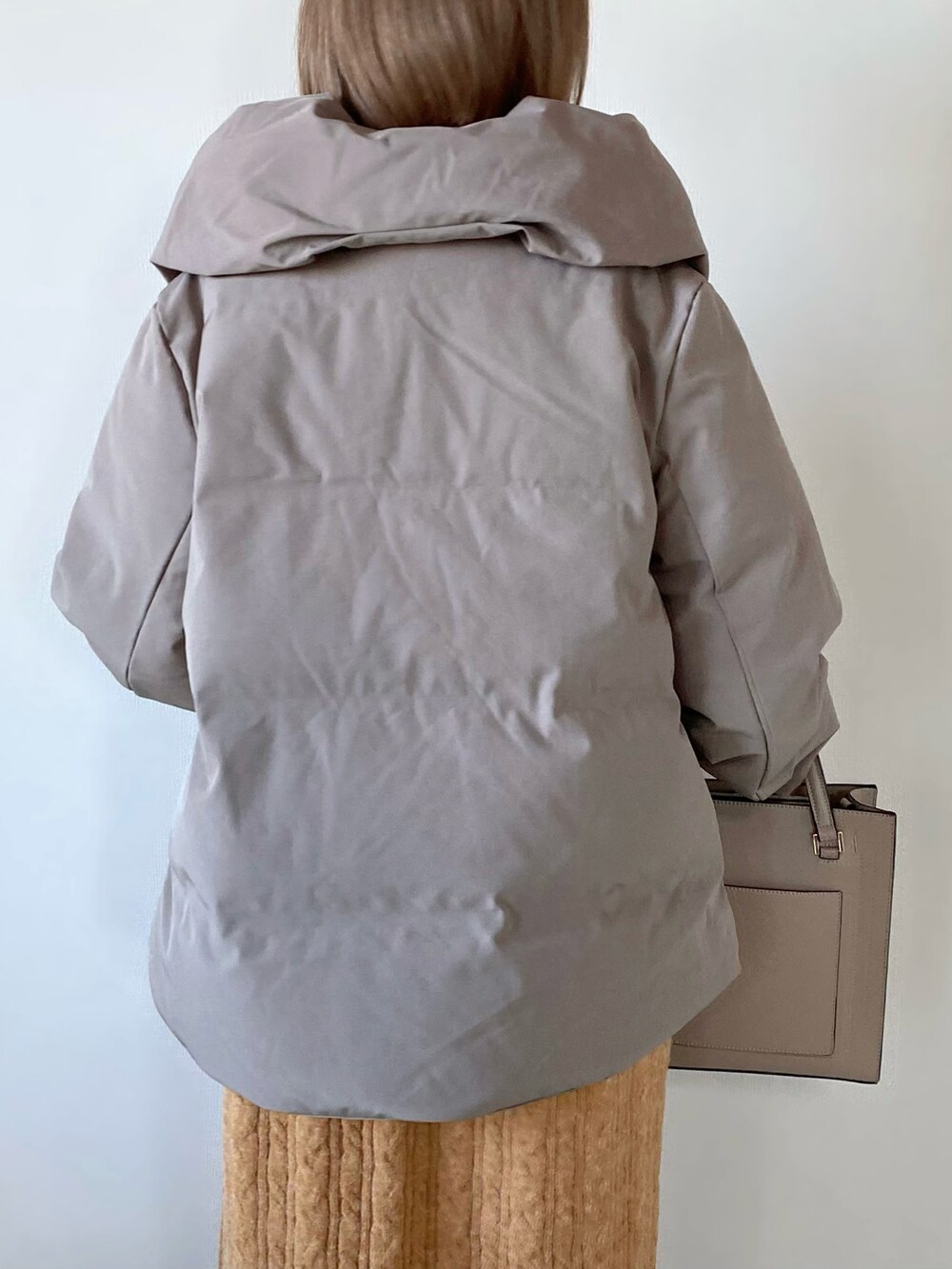 ブラウン系のダウンジャケット/コート、オレンジ系のワンピース、ベージュ系のバッグを着用したレディースの秋コーディネートの5枚目の写真