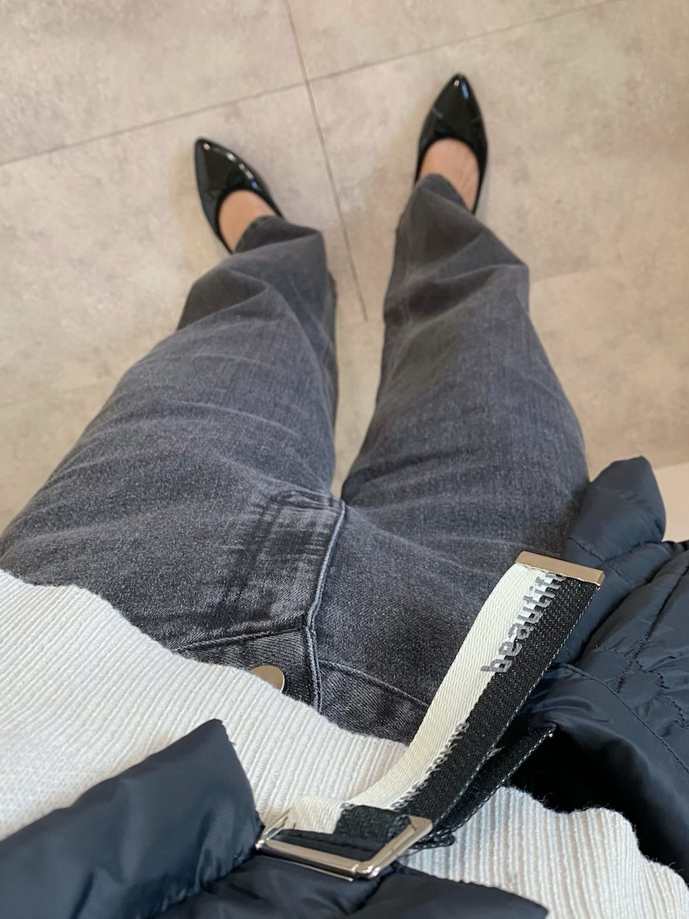 ブラック系のデニムパンツ、ブラック系のショルダーバッグ、ブラック系のパンプスを着用したレディースの冬コーディネートの3枚目の写真